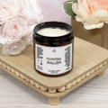 A jar of Cocoa Butter Cashmere Body Lotion placed on a wooden surface with flowers in the background.