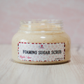 Jar of foaming sugar scrub with a label on a light background